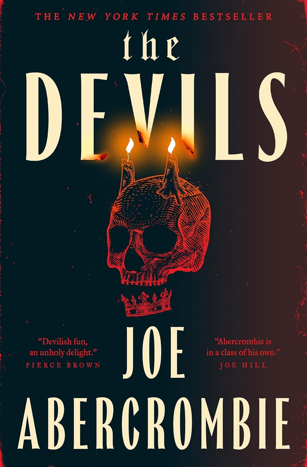 Book cover for 'The Devils' by Joe Abercrombie. A red-inked illustration of a horned skull wearing a small crown sits center, with two lit candles glowing above it like flames rising from the horns. The background is a dark teal-to-black gradient with faint red cracks along the edges. Text reads 'The New York Times Bestseller' at top, with blurbs from Pierce Brown ('Devilish fun, an unholy delight') and Joe Hill ('Abercrombie is in a class of his own') flanking the author's name at the bottom.